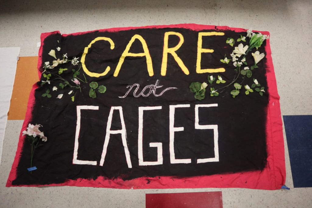 A banner with the words, care not cages on it, with flowers along the edges.